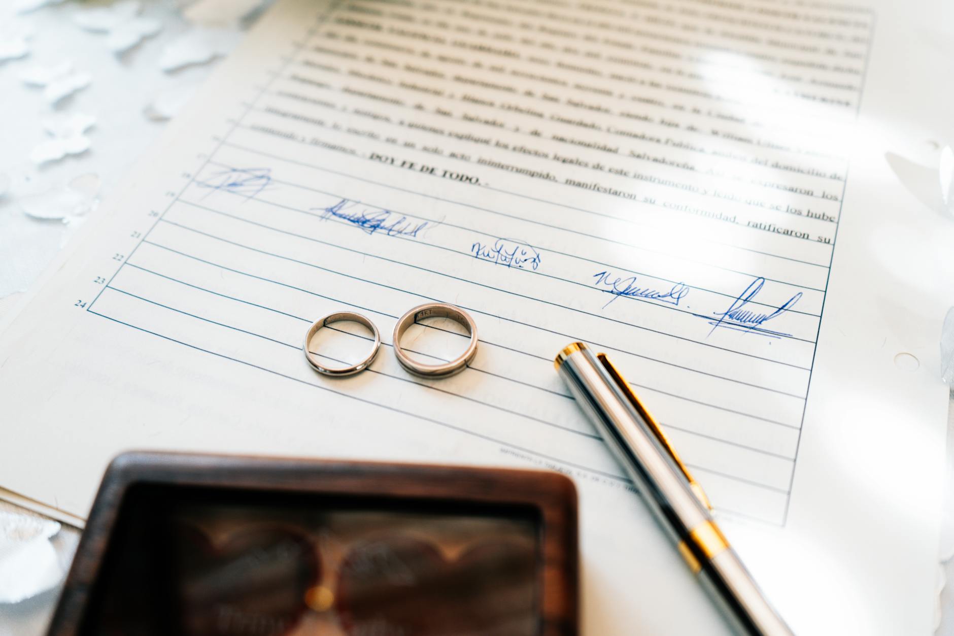 Elegant wedding rings laid on a signed marriage certificate, symbolizing commitment.