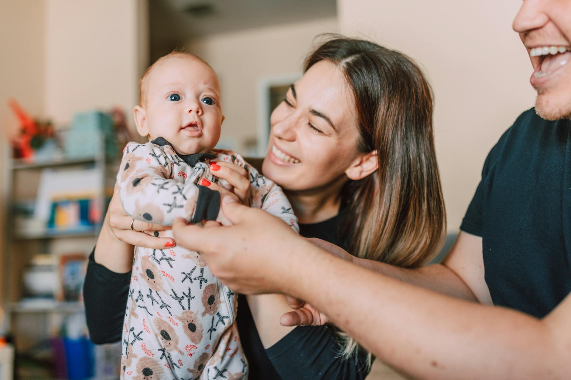A joyful family moment with parents holding their baby indoors, showcasing love and togetherness.