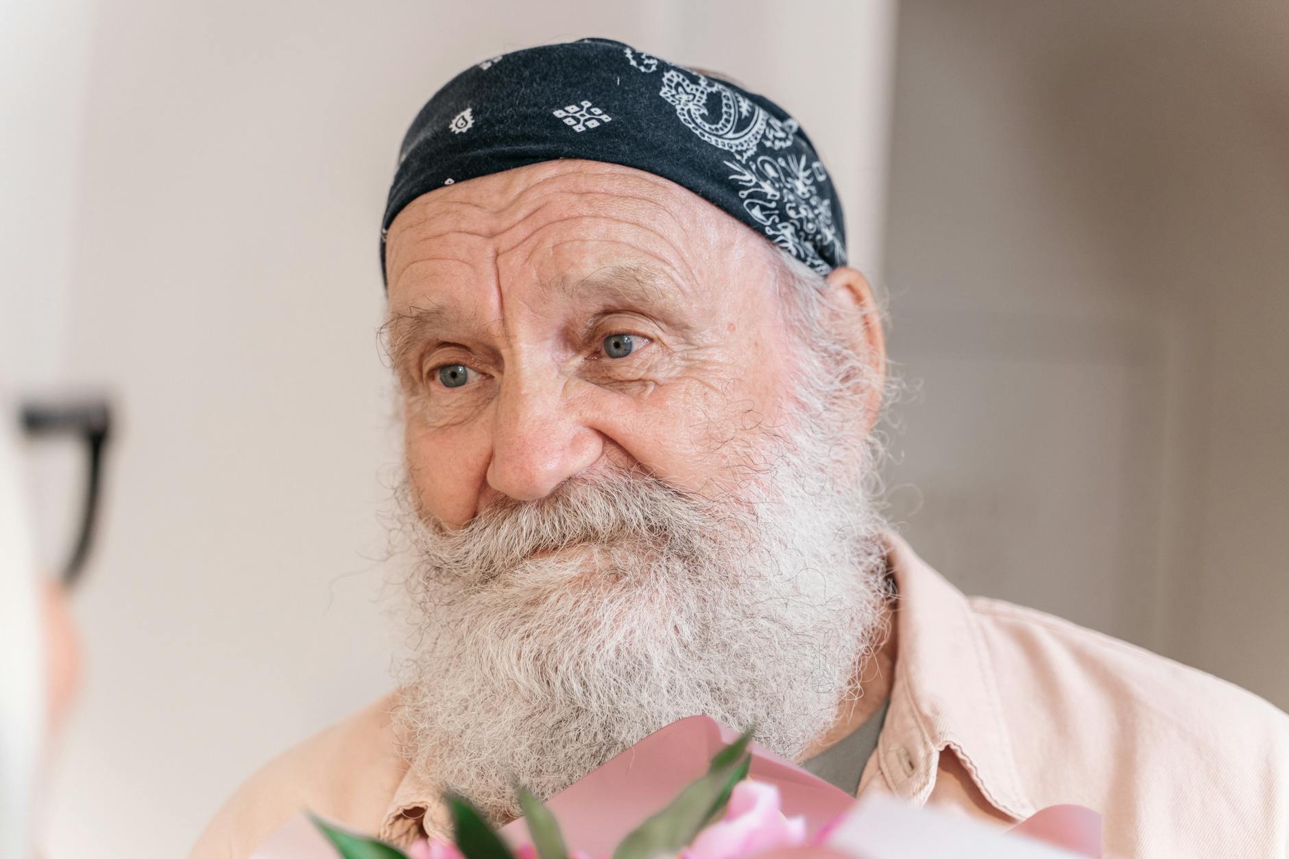 Close-up portrait of a senior man with a white beard and bandana, exuding warmth and friendliness.