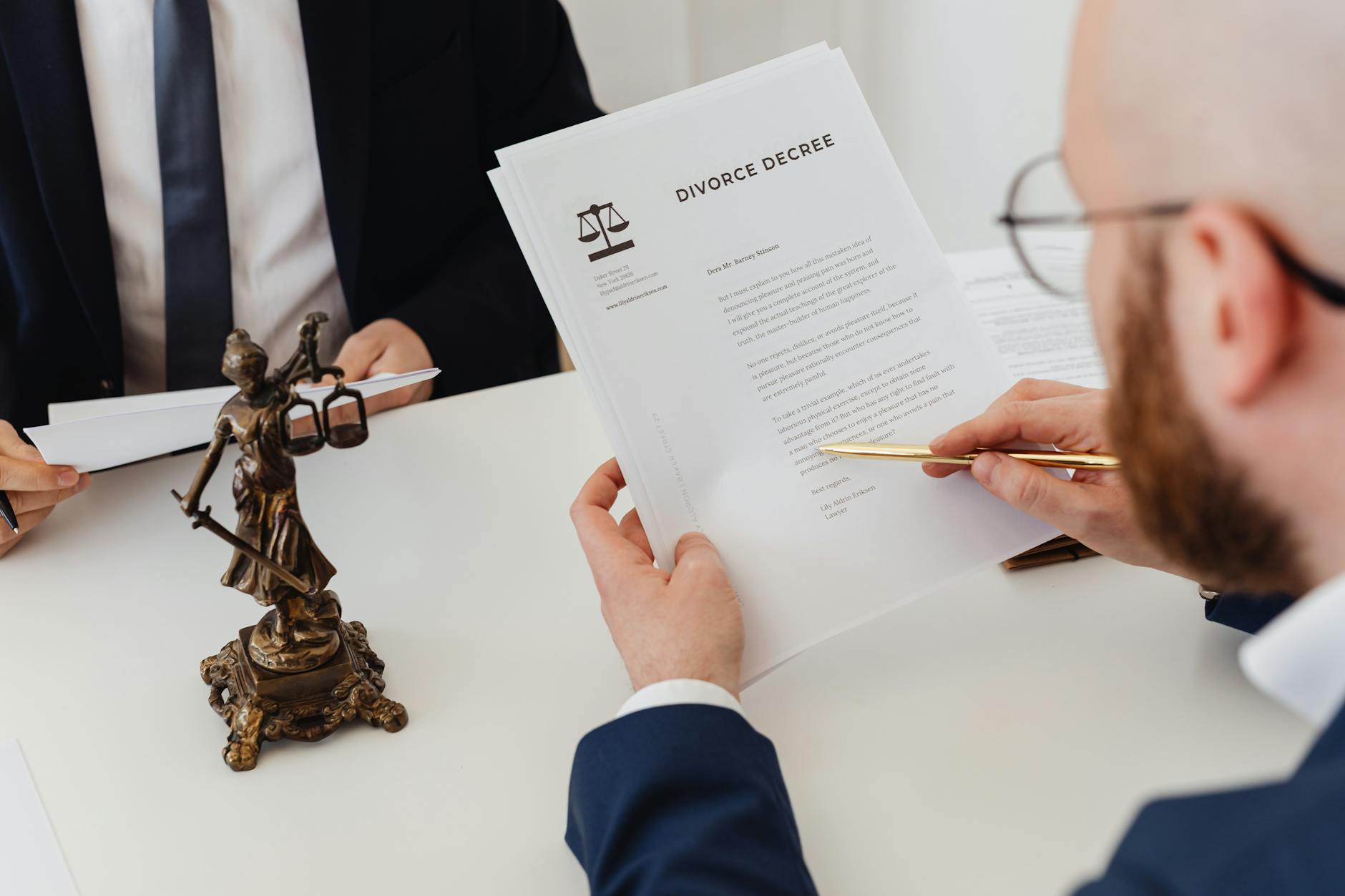 Two professionals examining a divorce decree with a Lady Justice statue nearby.