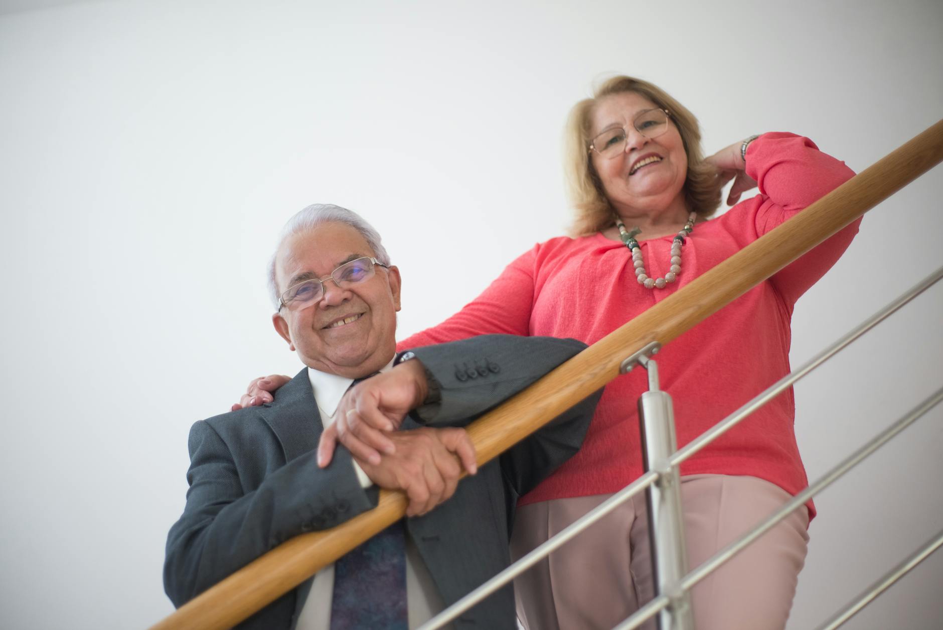 Happy senior couple posing on a contemporary staircase indoors in Portugal.